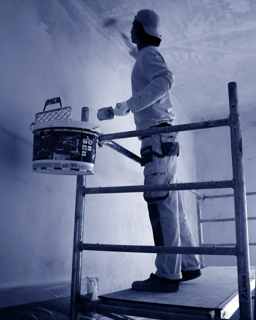 Peintre KMS appliquant de la peinture sur un mur intérieur